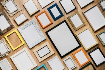 Assorted empty picture frames—ornate, wood, metal and colourful arranged on a timber surface