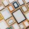 Assorted empty picture frames—ornate, wood, metal and colourful arranged on a timber surface